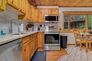 Une cuisine compacte avec des meubles en bois, un four à micro-ondes, un four et un lave-vaisselle en acier inoxydable.