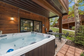 Een houten chalet met een jacuzzi, terrasmeubels buiten en een terras.