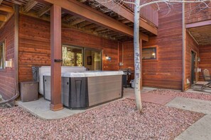 A wooden cabin with a hot tub, a grill, and a covered patio area. - Updated Riverfront Retreat • A/C • Private Hot Tub (Estes Park)