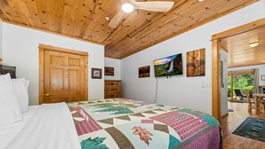 A bedroom with a large bed, wooden ceiling, and a view of the outdoors. - River Retreat • River Views • Near RMNP (Estes Park)