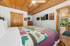 Une chambre avec un grand lit, un plafond en bois et une vue sur l’extérieur.