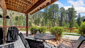 An outdoor patio with a grill, chairs, and a table. - River Retreat • River Views • Near RMNP (Estes Park)