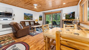 A cozy living room with a wooden ceiling, a fireplace, a dining table, and a sofa. - River Retreat • River Views • Near RMNP (Estes Park)