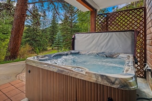 Un bain à remous avec une structure extérieure en bois, entouré d’une terrasse en bois et d’une clôture à treillis.