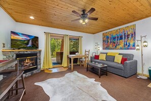 A cozy living room with a fireplace, a television, a sofa, and a large painting.