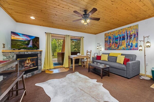 A cozy living room with a fireplace, a television, a sofa, and a large painting.