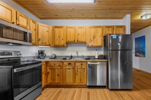 A modern kitchen with wooden cabinets, stainless steel appliances, and a wooden floor.