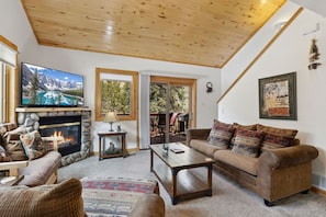 A cozy living room with a fireplace, comfortable seating, and a television. - Fall River Retreat • Private Hot Tub (Estes Park)