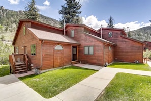 A two-story wooden house with a front porch, a garage, and a well-maintained lawn. - Fall River Retreat • Private Hot Tub (Estes Park)