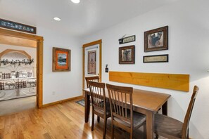 A dining area with a wooden table and chairs, framed artwork on the walls, and a sign indicating a Colorado location.