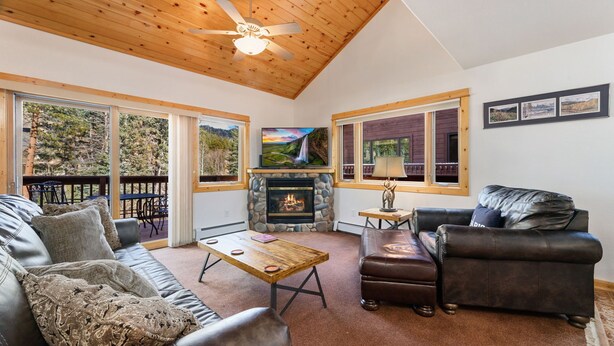 Una sala de estar acogedora con chimenea, mobiliario de cuero y grandes ventanas que ofrecen vistas al exterior.