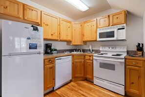 A kitchen with wooden cabinets, a refrigerator, a microwave, a dishwasher, and a stove.