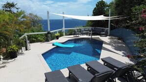 Une piscine avec des chaises longues et vue sur l’océan.