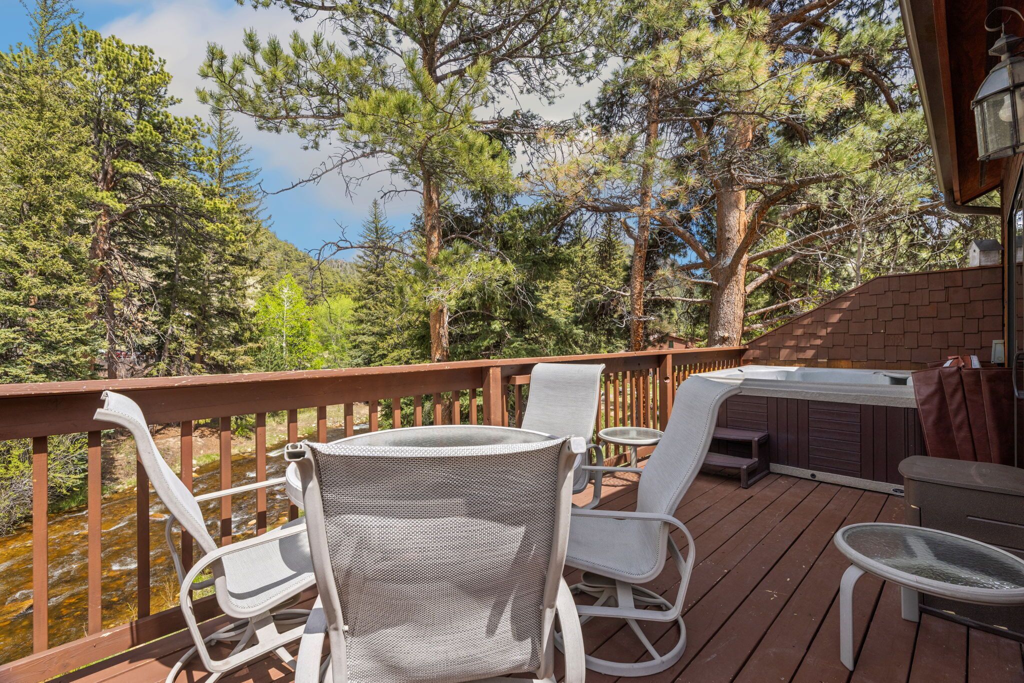 Eine Terrasse mit Sitzgelegenheiten im Freien, einem Whirlpool und Blick auf ein bewaldetes Gebiet.