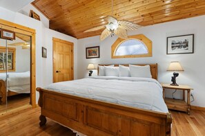 A bedroom with a wooden bed, a wooden ceiling, a window with a view, and a door labeled 'Owner's Closet'. - Riverfront Hideaway • Private Hot Tub • Near RMNP (Estes Park)