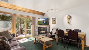 Una sala de estar acogedora con chimenea, televisor y comedor con sillas y mesa.