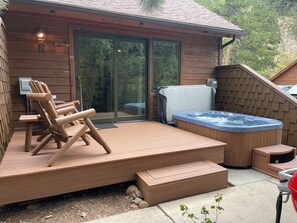 A wooden deck with outdoor furniture, a hot tub, and a staircase leading to a covered area. - Fall River Hideaway • Private Hot Tub • Near RMNP (Estes Park)