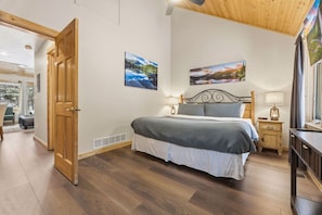 A bedroom with a bed, a nightstand, a window, and two paintings on the wall. - Fall River Hideaway • Private Hot Tub • Near RMNP (Estes Park)