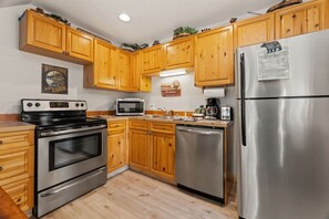 A kitchen with wooden cabinets, stainless steel appliances, a microwave, and a refrigerator.