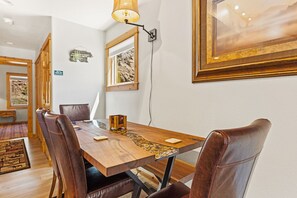 A dining area with a wooden table, leather chairs, a lamp, and a framed picture on the wall.