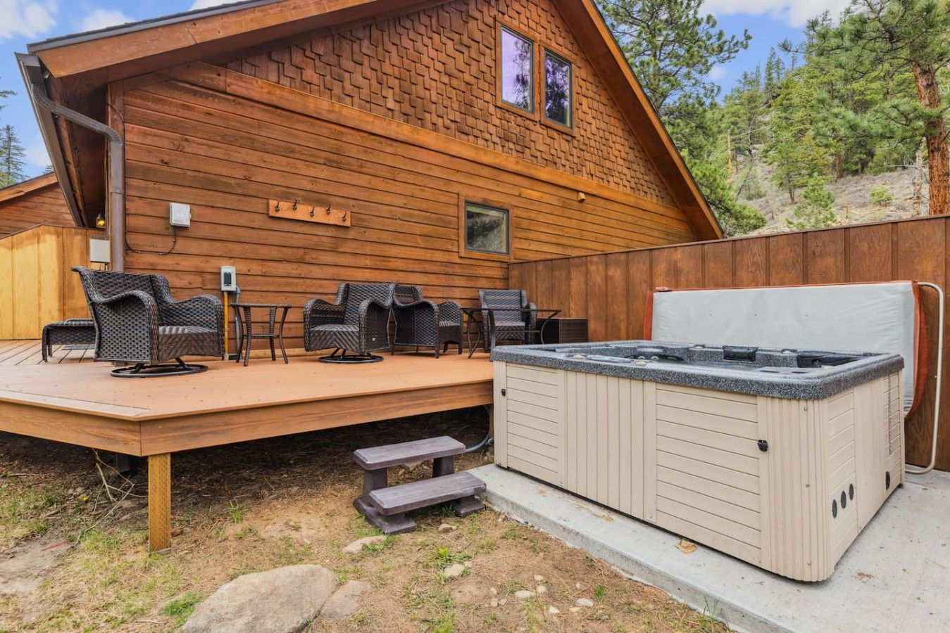 A wooden cabin with a hot tub, outdoor seating, and a deck.