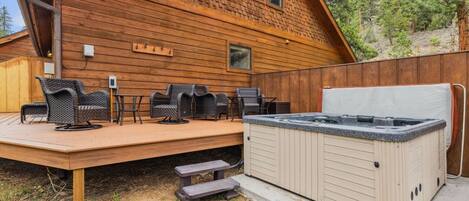 A wooden cabin with a hot tub, outdoor seating, and a deck.