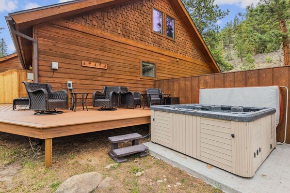 A wooden cabin with a hot tub, outdoor seating, and a deck.