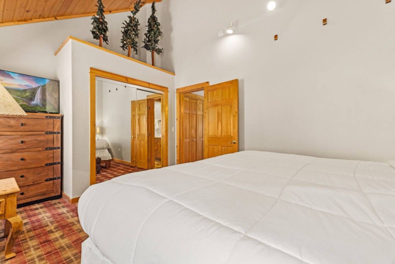 Une chambre avec un grand lit, une armoire en bois et un tableau accroché au mur.