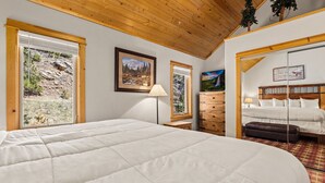 Une chambre à coucher avec un grand lit, une commode, une table de chevet et un tableau au mur.