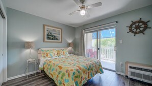 A bedroom with a bed, a ceiling fan, a window, and a view of the outdoors.