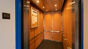 An elevator with wooden walls, a blue door frame, and a sign with a star symbol.