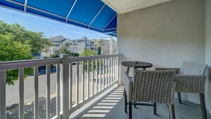 A balcony with a blue awning, wicker chairs, and a small table.