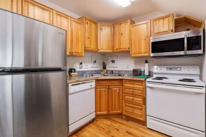 A kitchen with wooden cabinets, stainless steel appliances, and a tiled backsplash.