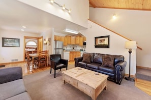 A spacious living room with a sofa, coffee table, and a dining area with chairs and a table.