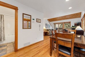 A wooden dining table with chairs, a kitchen area with a stove, and a living room with a sofa. - Riverfront Comfort • Peaceful • Near RMNP (Estes Park)