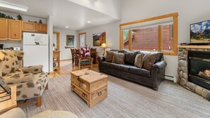 A spacious living room with a fireplace, a dining area, and a kitchen. - Fall River Retreat • Mountain Views • RMNP (Estes Park)