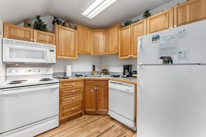 A kitchen with wooden cabinets, a white refrigerator, a microwave, a stove, and a dishwasher.
