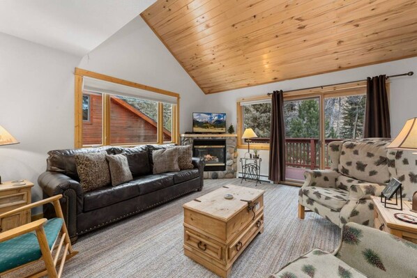 A cozy living room with a fireplace, a sofa, a coffee table, and a view of the outdoors.
