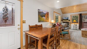 A cozy living room with a wooden dining table, a sofa, and a TV. - Fall River Retreat • Mountain Views • RMNP (Estes Park)