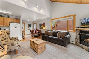 A spacious living room with a fireplace, a dining area, and a kitchen.