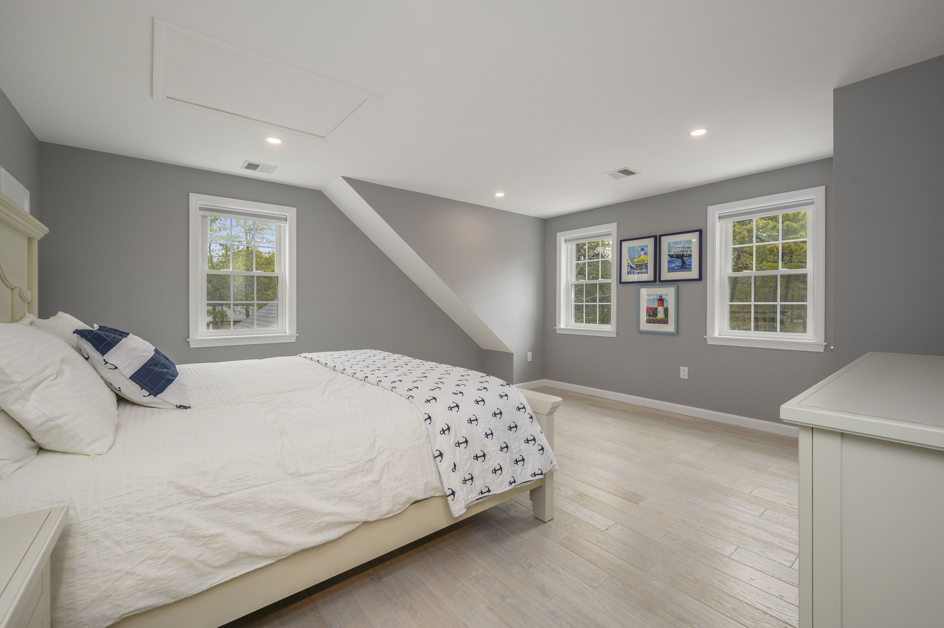 Une chambre à coucher avec un lit, deux fenêtres et un plafond en pente.