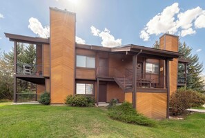 Un bâtiment moderne à deux étages, doté d’une façade en bois, de grandes fenêtres et d’un balcon avec un escalier.