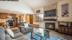 Una sala de estar moderna con chimenea, un televisor grande y una zona de estar acogedora.