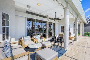 Relax in style on this outdoor patio, complete with lounge chairs and a small table, under a shaded roof with a ceiling fan.