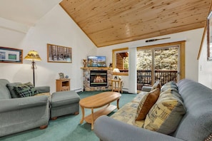 A cozy living room with a fireplace, a sofa, a coffee table, and a television. - Peaceful Fall River Escape • River Views • RMNP (Estes Park)