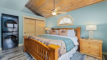 A bedroom with a wooden bed, a ceiling fan, a washing machine, and a wooden dresser.