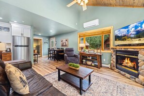 A living room with a fireplace, a television, and a dining area with chairs and a table. - Riverfront Escape • A/C • Near RMNP (Estes Park)