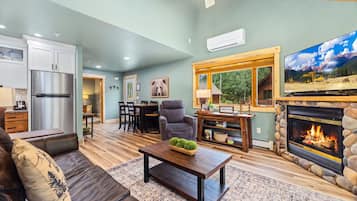A living room with a fireplace, a television, and a dining area with a table and chairs.
