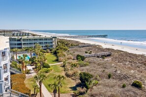 A coastal hotel with a beach view, a pool, and a pier.