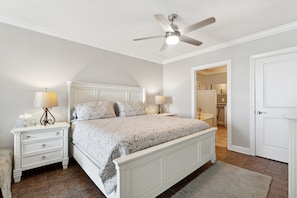 A bedroom with a bed, nightstands, a ceiling fan, and a bathroom visible through an open door.